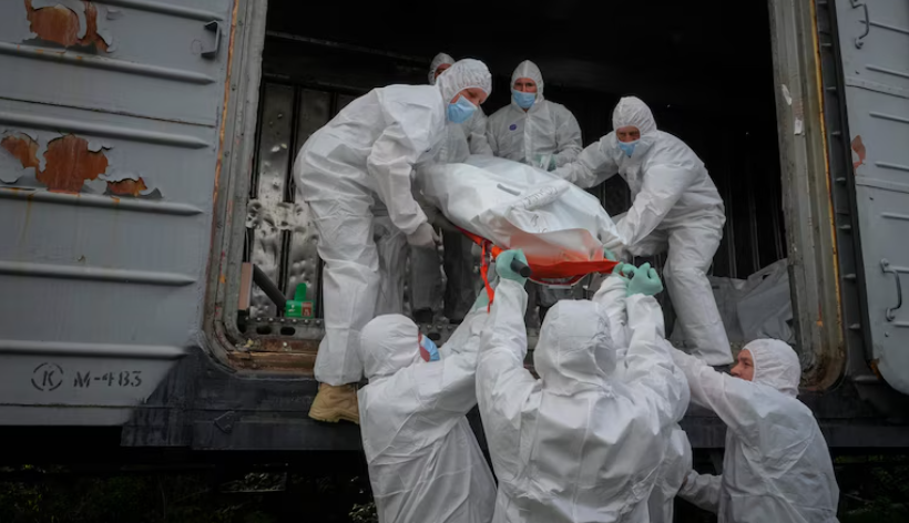 Workers carrying bodies from a morgue train to clear the dead from Ukrainian war battlefield.
