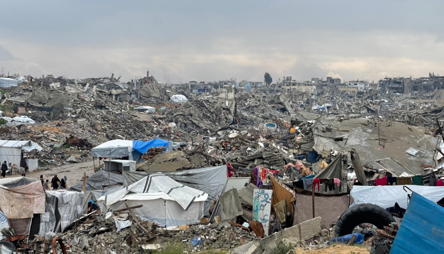 A photograph of a city block of rubble with tents where Gazans are living.