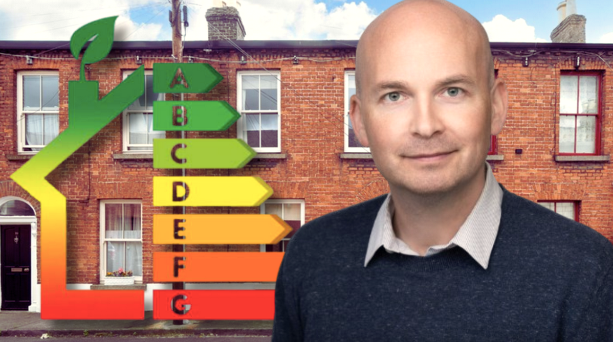 Paul Murphy next to the familar Building Energy Rating Scale in front of a terrace of homes.