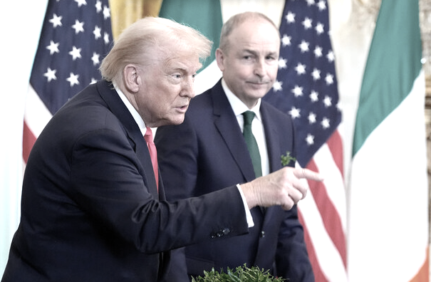 Trump points over a bowl of Shamrocks in Washington as Micheál Martin looks on silently.