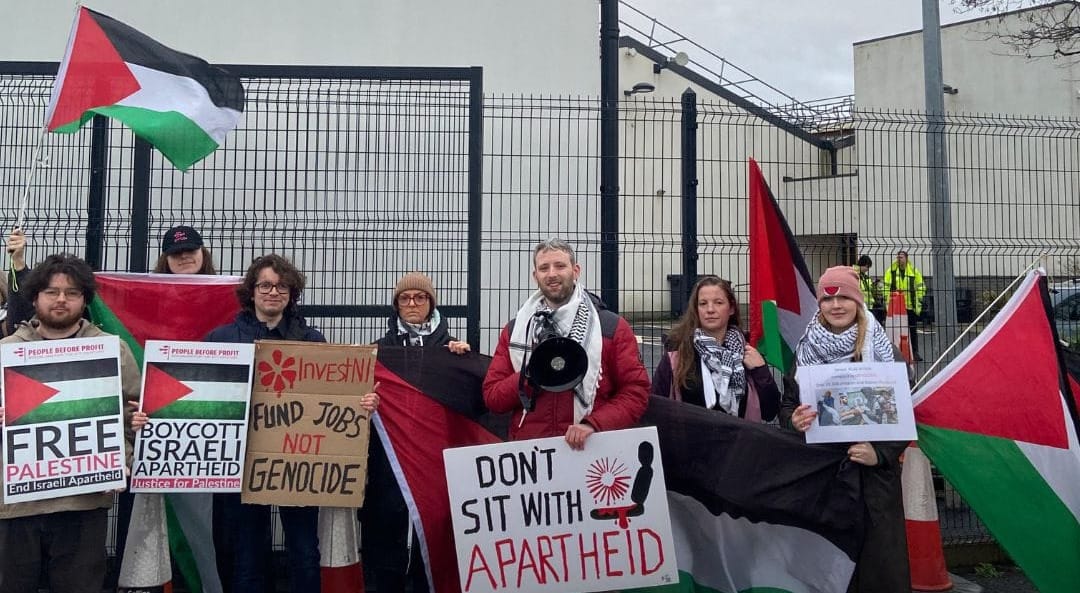 Pro-Palestine Protest at Collins Aerospace in Kilkeel. Palestine flags. Posters saying 'Free Palestine', 'Fund Jobs Not Genocide', 'Boycott Israel Apartheid',  and 'Don't Sit With Apartheid'.