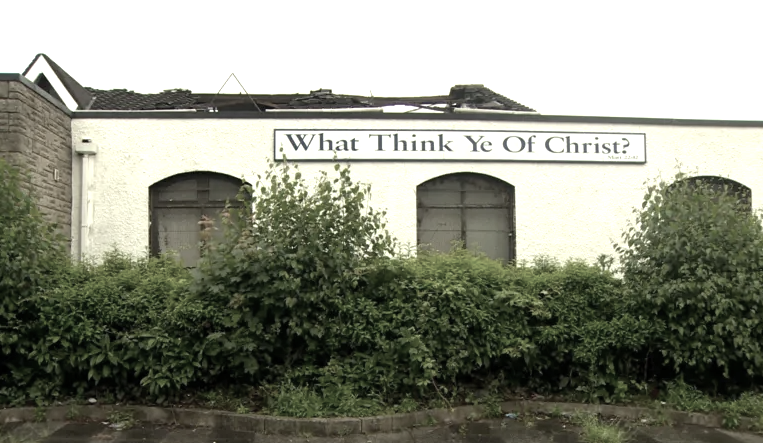 The building attacked by an arsonist in Belfast was a disused church. Image shows the destroyed roof above a sign saying What Think Ye Of Christ? Building's previous use was as a church.