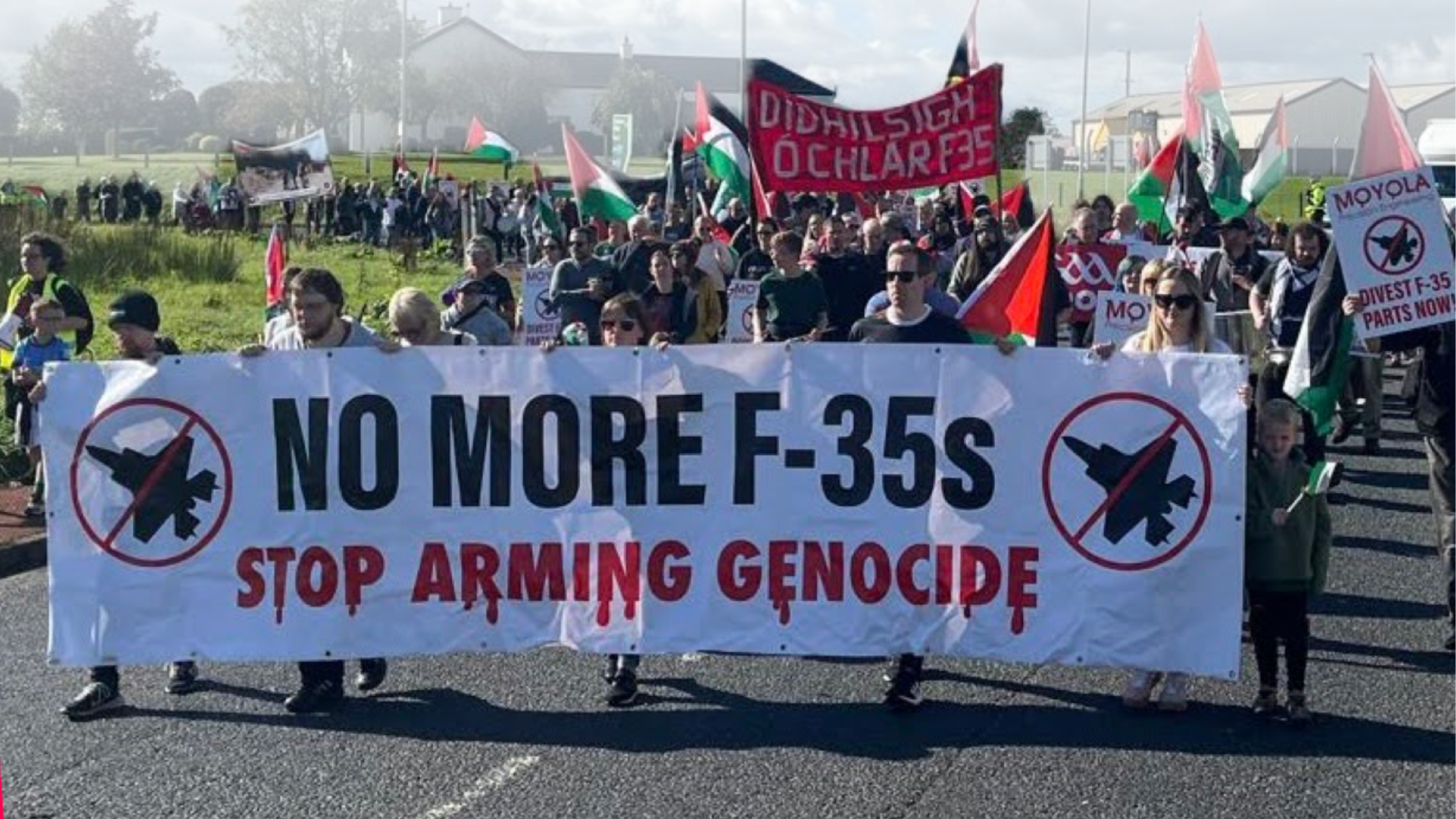 300 marchers carrying placards and Palestine flags behind a banner saying NO MORE F-35s STOP ARMING GENOCIDE