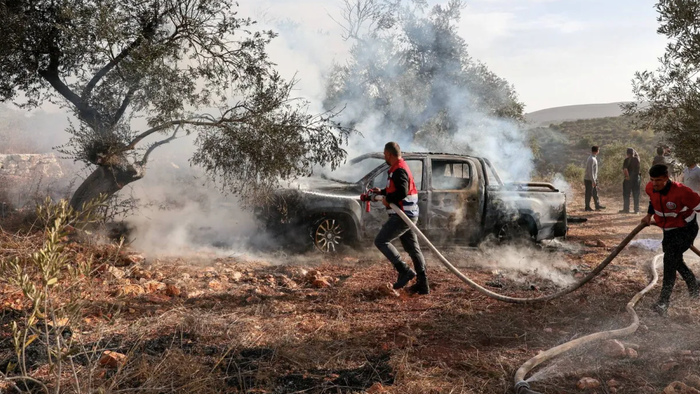 Firefighters douse a burnt car with water after Israeli militant settlers attacked a group of Palestinians harvesting olives near Turmus Ayya in the Israeli-occupied West Bank, October 16, 20
