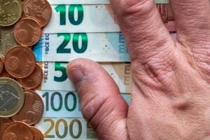 Hand fingers on background of neatly arranged stack of euro banknotes, currency bills worth ten