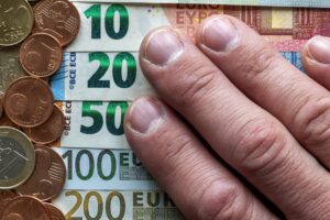 Hand fingers on background of neatly arranged stack of euro banknotes, currency bills worth ten